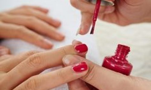 Woman having her nails painted classic red color